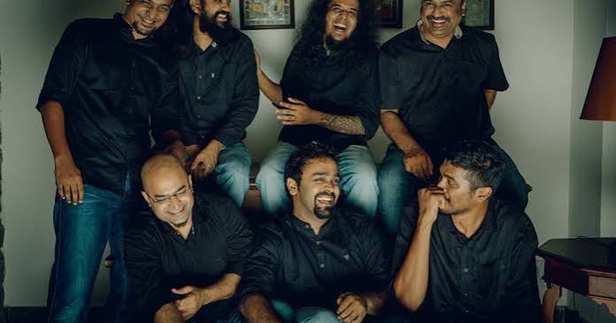 AGAM together in a warm indoor room, laughing, wearing black shirts and jeans.
