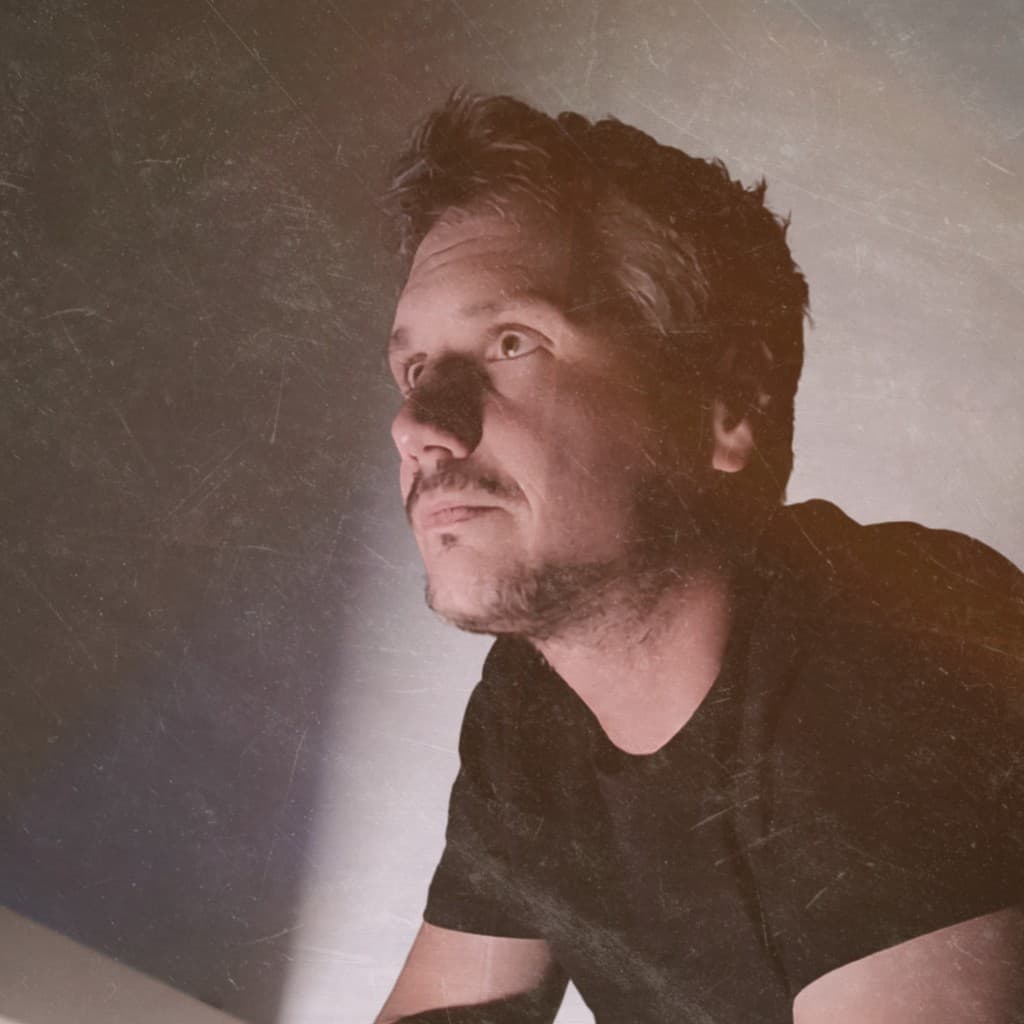 LAWIJT. (Niels Strybos): a low-lit portrait looking off frame, light falling across his face.