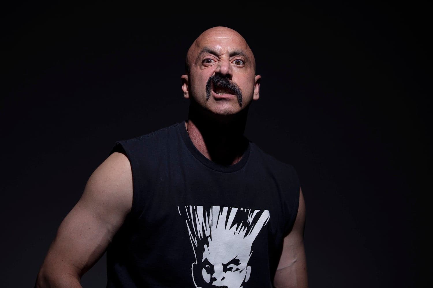 N8NOFACE in a sleeveless black tee, mid-snarl against a dark background.