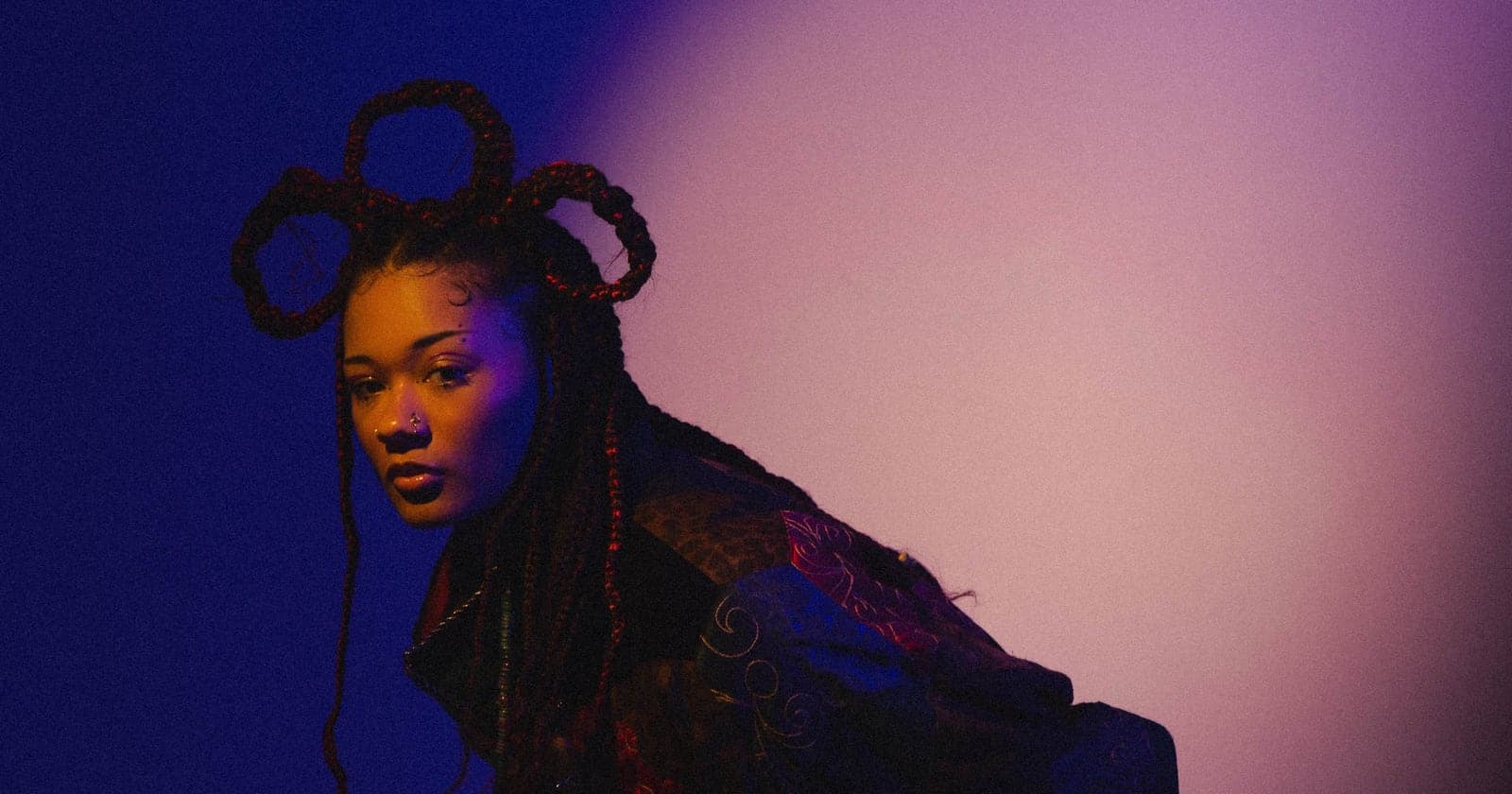 Nyota Parker with looped braids, leaning into purple and blue light.
