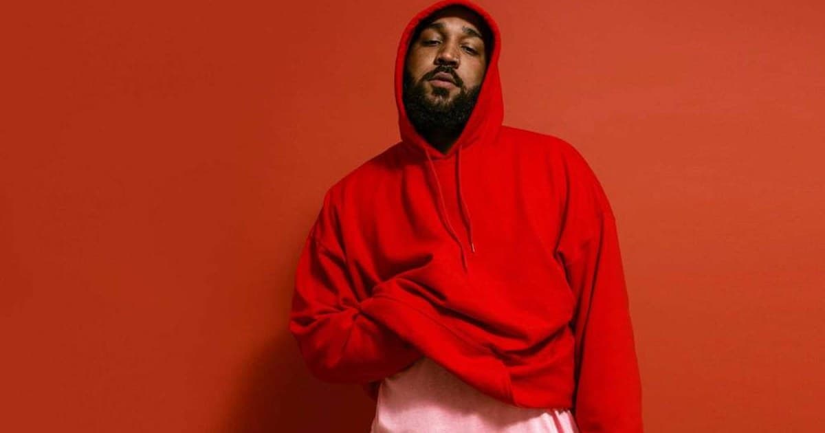 OG Keemo photographed in a bright red hooded sweatshirt against a matching red backdrop.