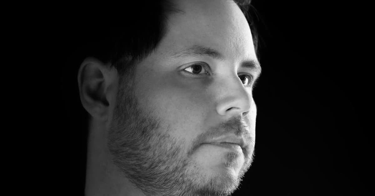 Black-and-white portrait of Ryan Farish in profile light against a black background.