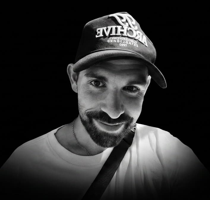 TELN (Markus): a black-and-white portrait in an ARCHIVE cap and thin chain against a dark background.